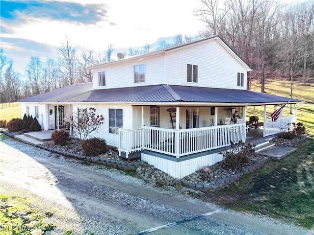 farmhouse featuring covered porch and metal roof