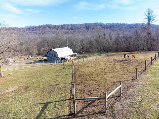 view of yard with a rural view, an outdoor structure, a barn, and fence