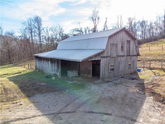 view of barn featuring driveway and fence