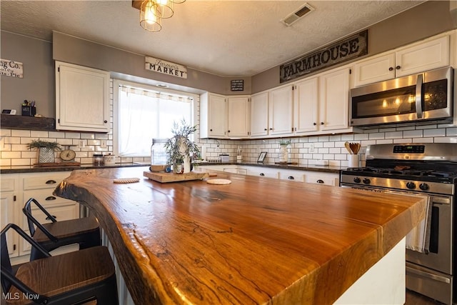 kitchen with visible vents, white cabinetry, and stainless steel appliances