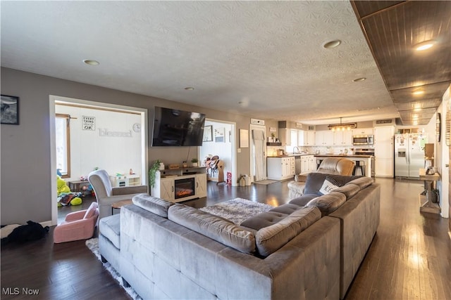 living area featuring a fireplace, a textured ceiling, and wood finished floors