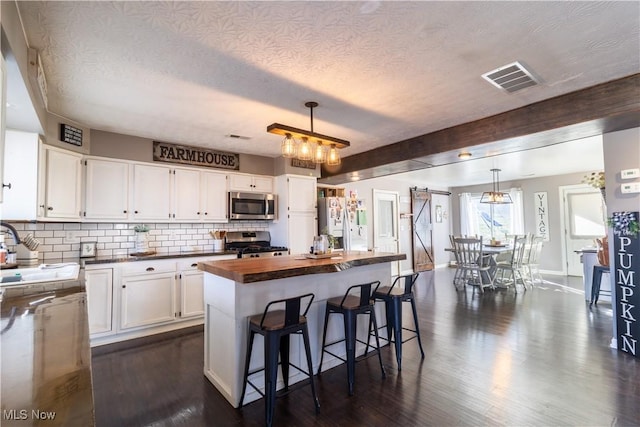 kitchen featuring a kitchen island, white cabinetry, stainless steel appliances, and pendant lighting