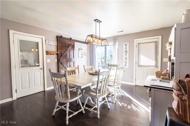 dining area featuring a barn door, visible vents, baseboards, and dark wood-type flooring