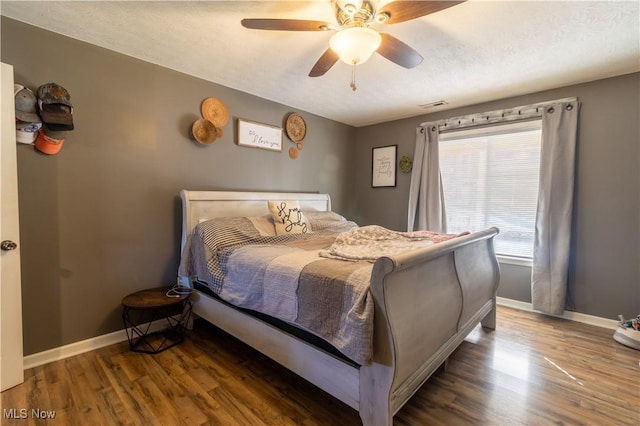 bedroom with visible vents, dark wood-type flooring, ceiling fan, a textured ceiling, and baseboards