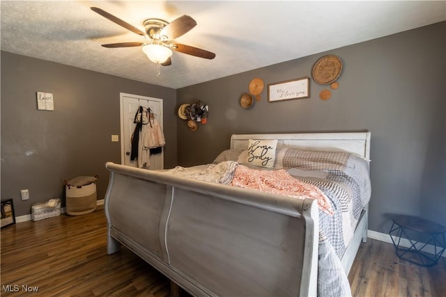 bedroom with dark wood-style floors, a closet, baseboards, and a ceiling fan