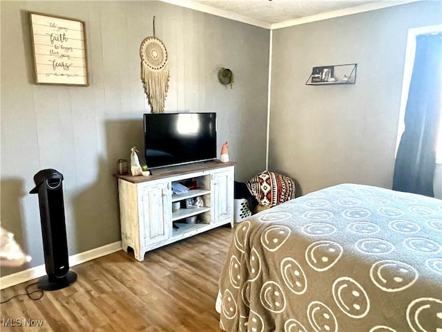 bedroom featuring ornamental molding, baseboards, and wood finished floors