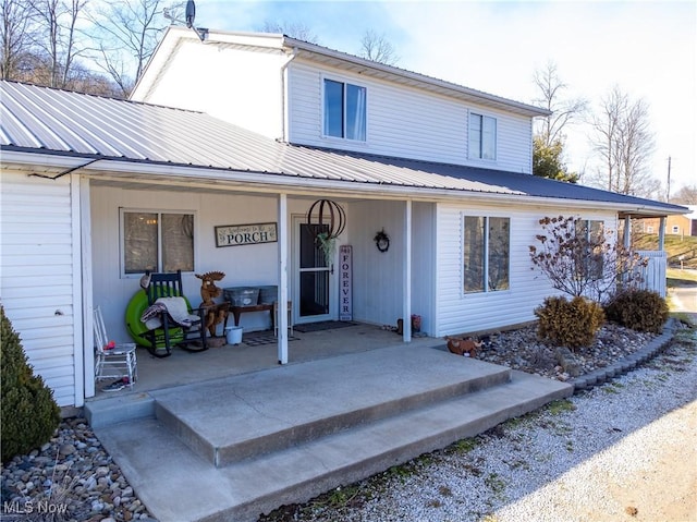 view of front of property featuring a porch, metal roof, and a patio