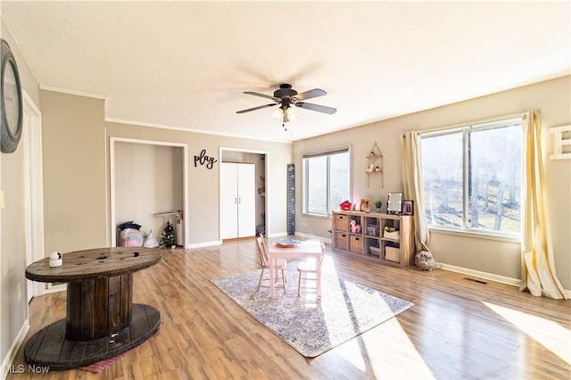 interior space featuring visible vents, light wood finished floors, a ceiling fan, and baseboards