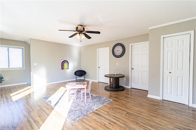 living area featuring ceiling fan, wood finished floors, and baseboards