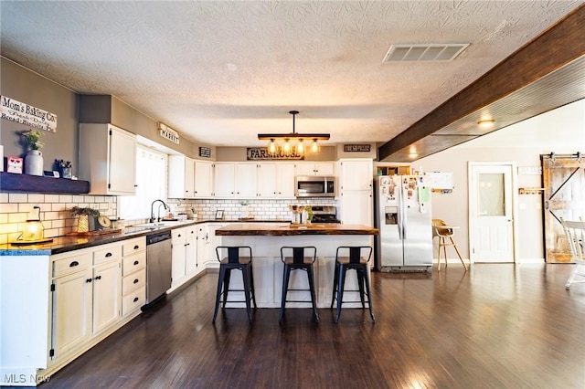 kitchen with dark countertops, visible vents, appliances with stainless steel finishes, white cabinets, and a kitchen island