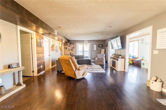 living area featuring a textured ceiling, dark wood-type flooring, and baseboards