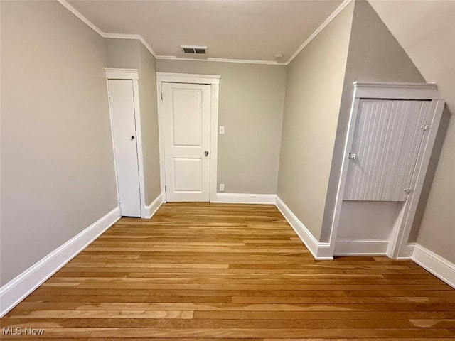 corridor with light hardwood / wood-style flooring and ornamental molding