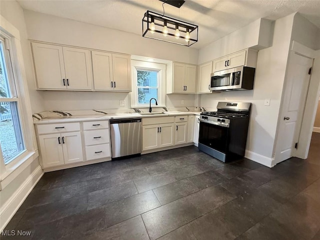 kitchen featuring white cabinetry, appliances with stainless steel finishes, sink, and decorative light fixtures