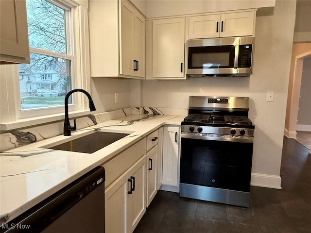 kitchen with light stone counters, sink, stainless steel appliances, and white cabinets