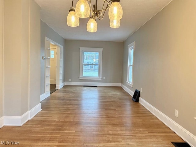 unfurnished dining area featuring light hardwood / wood-style flooring and a notable chandelier