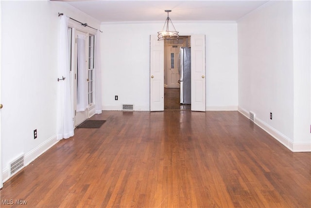 empty room with crown molding, dark hardwood / wood-style floors, and a notable chandelier