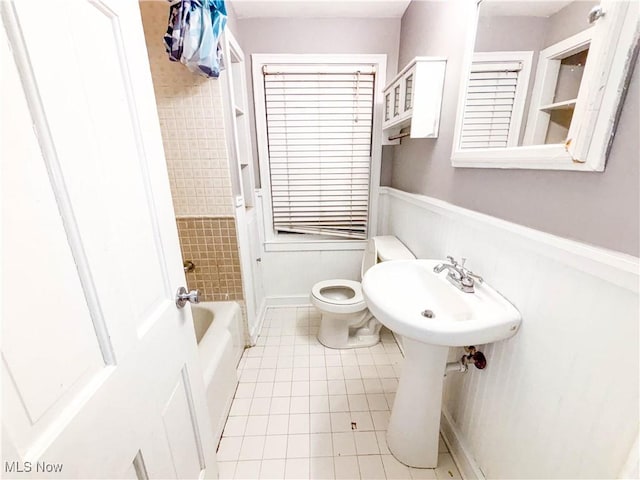 bathroom with tiled shower / bath, toilet, and tile patterned flooring