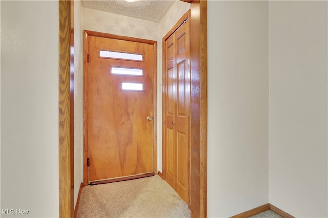 doorway to outside with a textured ceiling and carpet