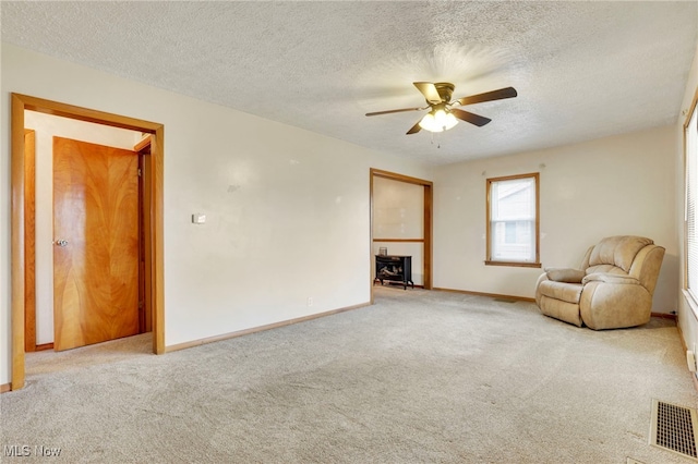 unfurnished room featuring ceiling fan, light carpet, and a textured ceiling