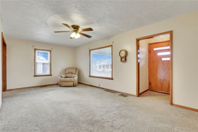 unfurnished room featuring ceiling fan, light colored carpet, and a textured ceiling