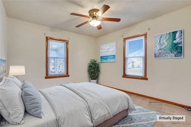 bedroom featuring ceiling fan, light carpet, and a textured ceiling