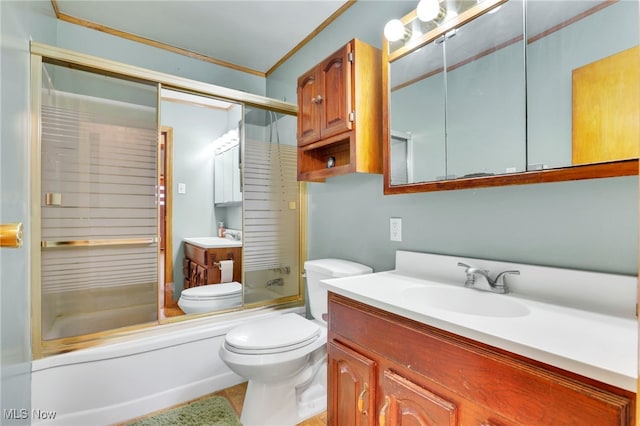 full bathroom featuring vanity, crown molding, toilet, and combined bath / shower with glass door