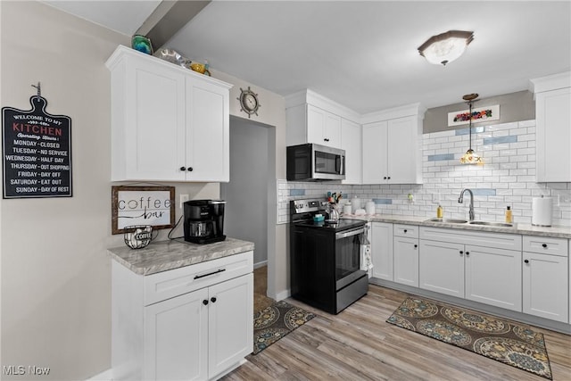 kitchen with sink, white cabinetry, stainless steel appliances, light hardwood / wood-style floors, and backsplash