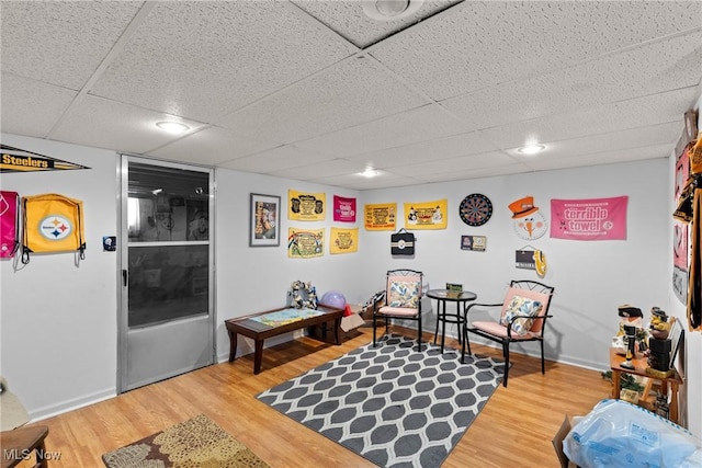 sitting room with hardwood / wood-style floors and a drop ceiling