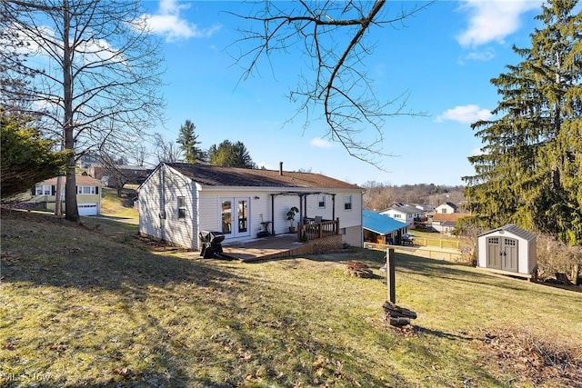 rear view of property with french doors, a yard, a deck, and a storage unit