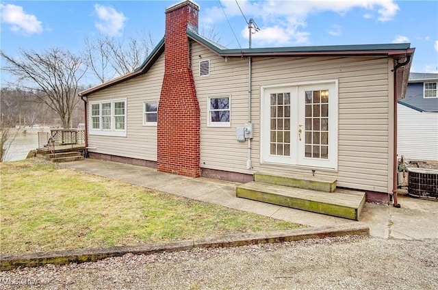 rear view of property with a lawn, central AC unit, and french doors