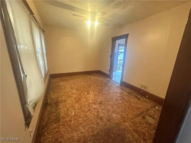 unfurnished room with ceiling fan and a textured ceiling