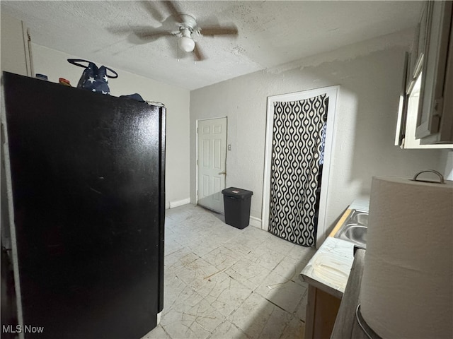 kitchen with sink, ceiling fan, a textured ceiling, and black fridge