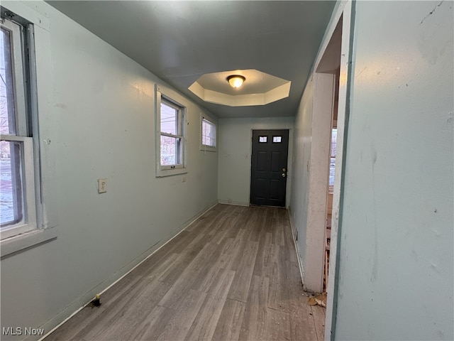 doorway to outside with a raised ceiling and light hardwood / wood-style flooring