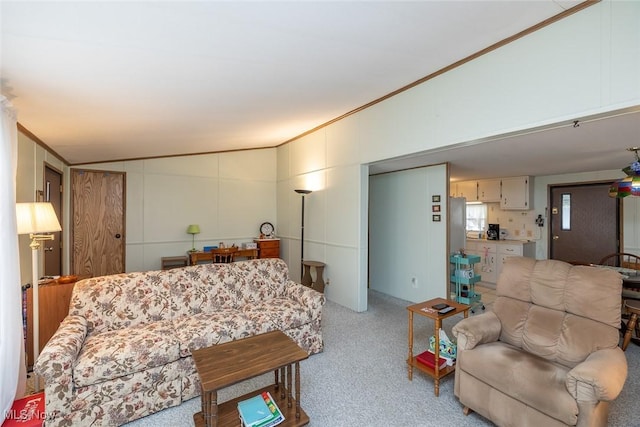 living room featuring light colored carpet, ornamental molding, and vaulted ceiling