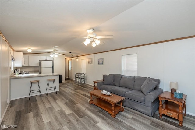 living room with lofted ceiling, hardwood / wood-style flooring, ornamental molding, and ceiling fan