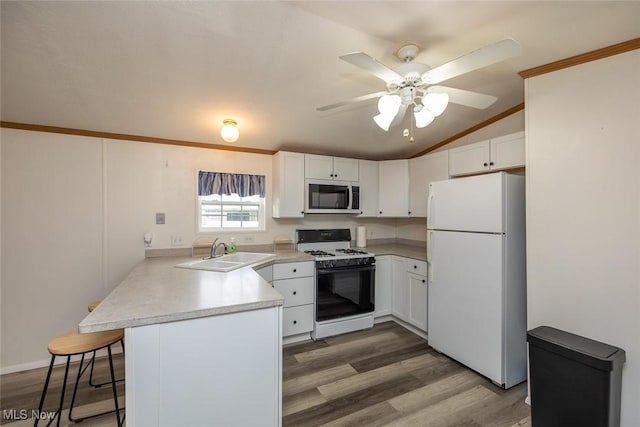 kitchen featuring sink, white appliances, a breakfast bar, white cabinetry, and kitchen peninsula