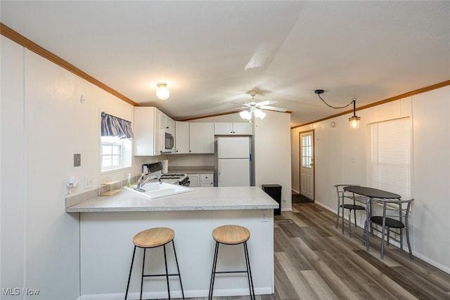 kitchen featuring white appliances, kitchen peninsula, sink, and white cabinets