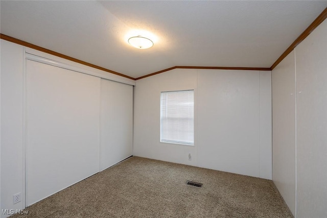 spare room featuring lofted ceiling, crown molding, and carpet flooring