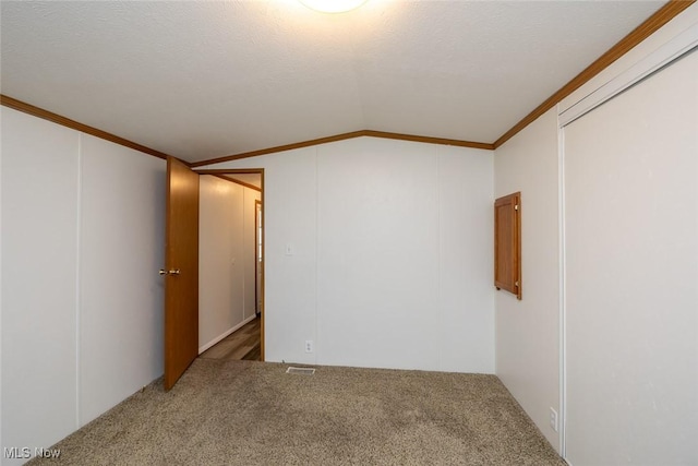 unfurnished room with vaulted ceiling, carpet, a textured ceiling, and crown molding