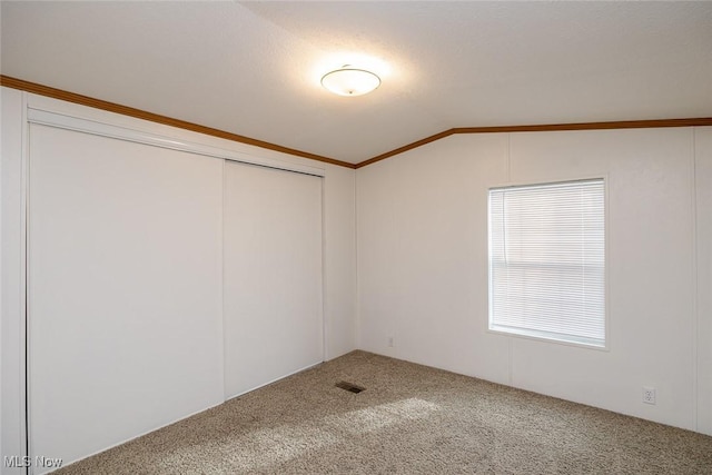 carpeted spare room with vaulted ceiling