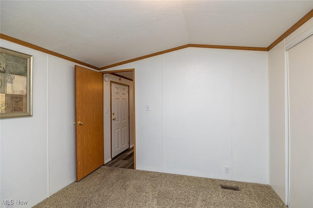 carpeted spare room featuring ornamental molding, vaulted ceiling, and a textured ceiling