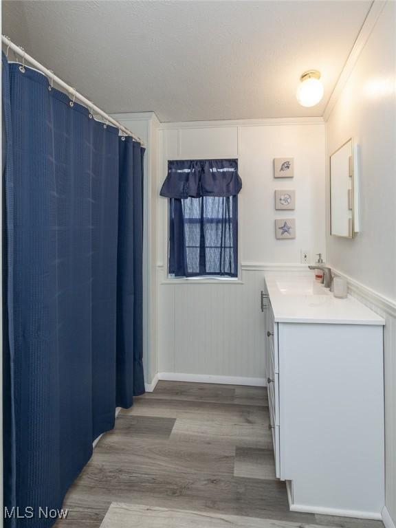 bathroom featuring crown molding, wood-type flooring, and vanity