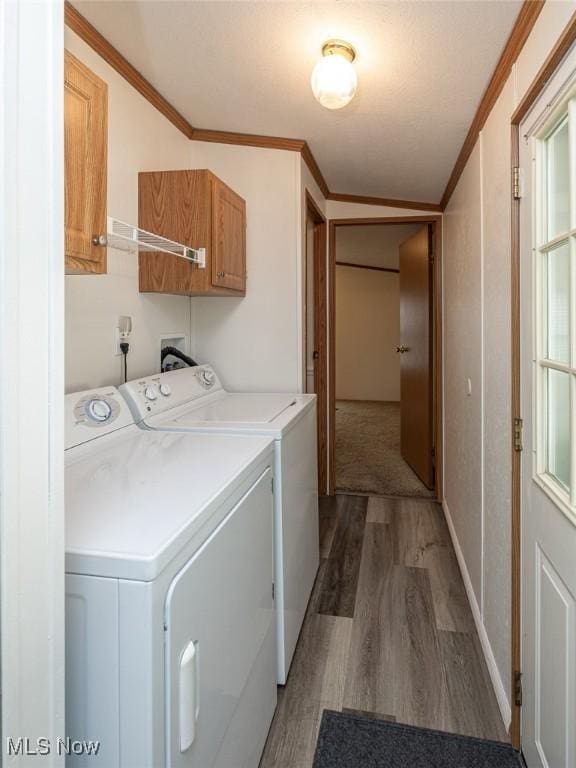 clothes washing area with dark wood-type flooring, cabinets, ornamental molding, and washer and dryer