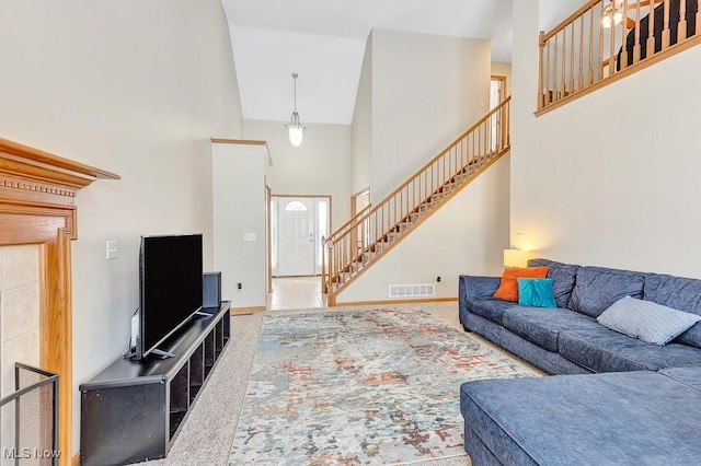 carpeted living area with stairs, a high ceiling, visible vents, and baseboards