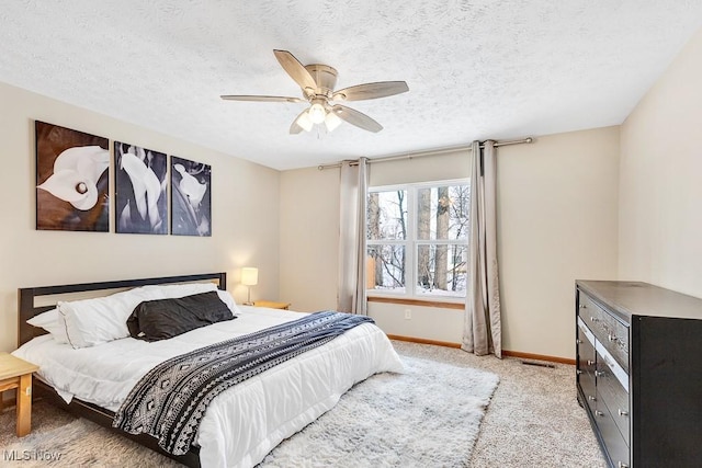 bedroom featuring ceiling fan, baseboards, a textured ceiling, and light colored carpet