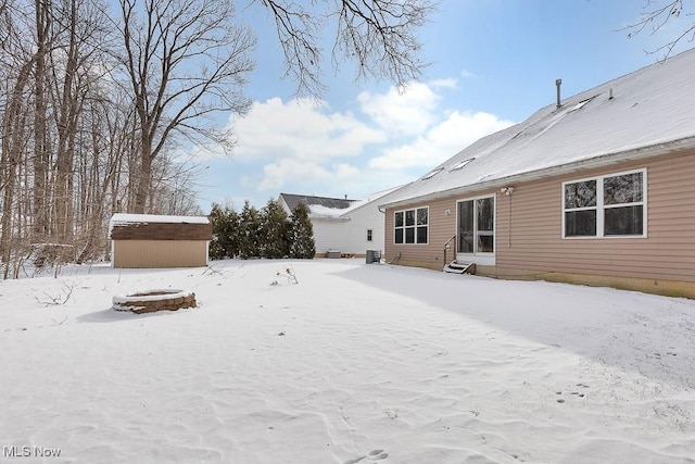 yard covered in snow featuring entry steps, an outdoor structure, and a storage unit