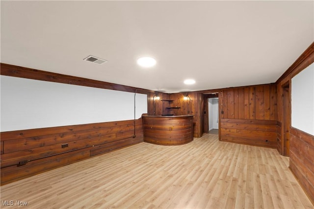 bar featuring light hardwood / wood-style flooring and wood walls