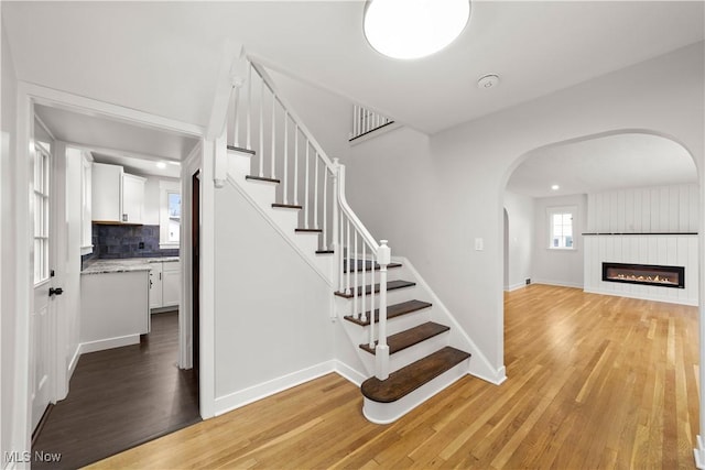 staircase featuring wood-type flooring and a large fireplace