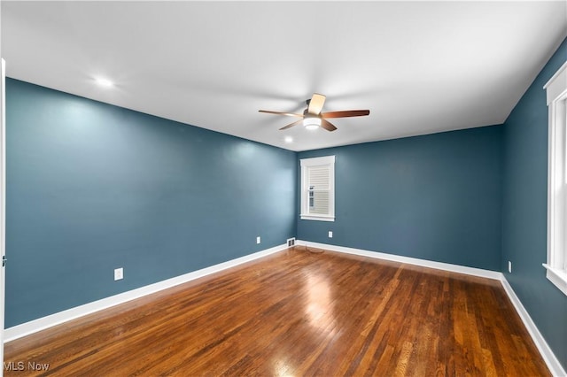 spare room featuring dark wood-type flooring and ceiling fan