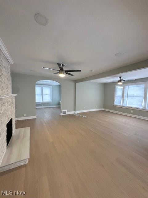 unfurnished living room with a stone fireplace, light hardwood / wood-style floors, and ceiling fan